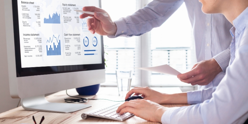 Two people reviewing financial charts on a computer screen.