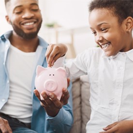 child putting money in a piggy bank