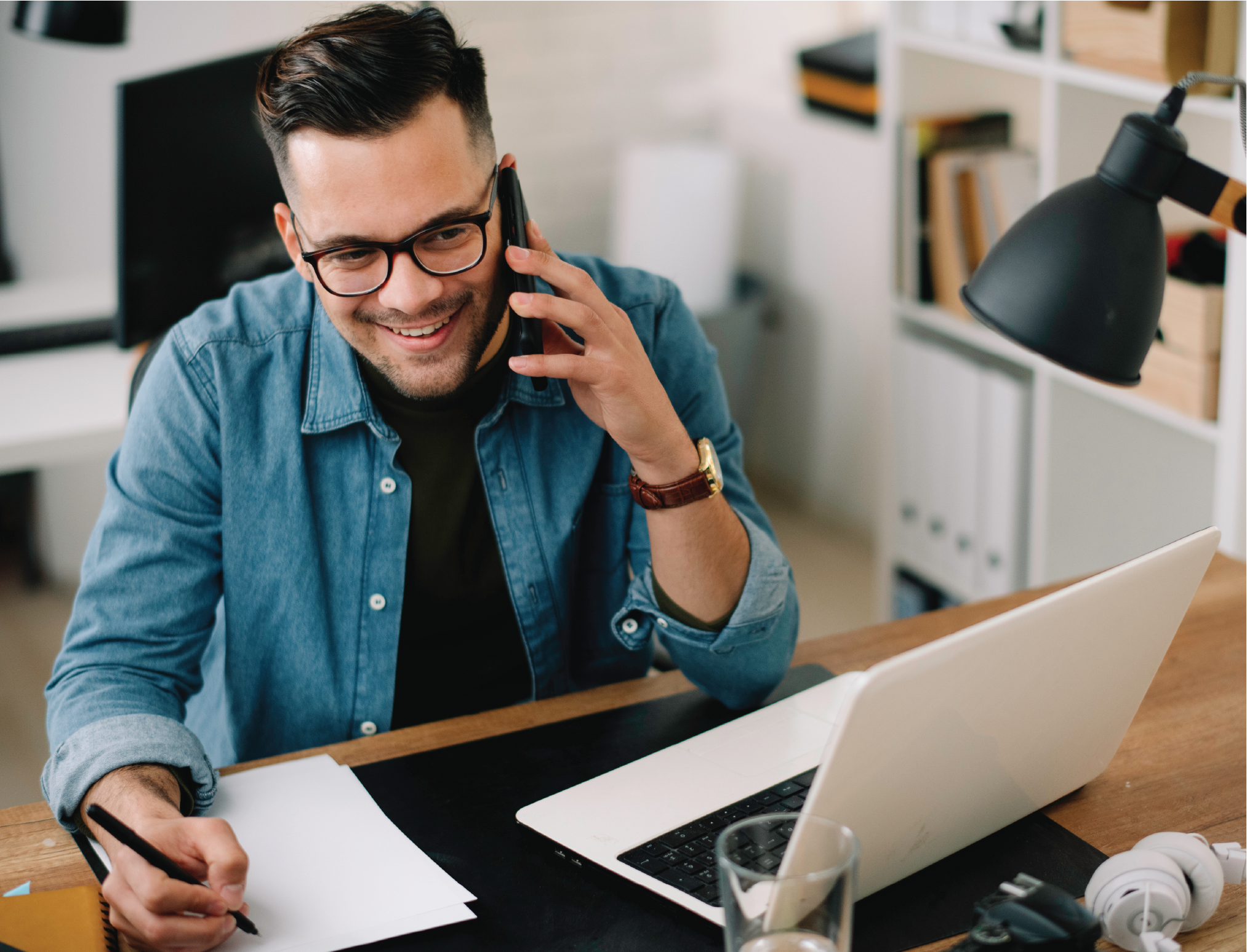 man happy on cellphone with pen and paper
