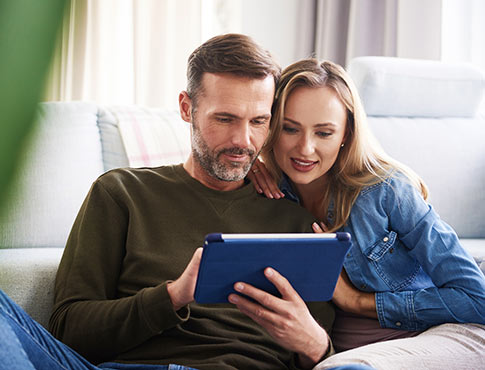 Couple using tablet in living room