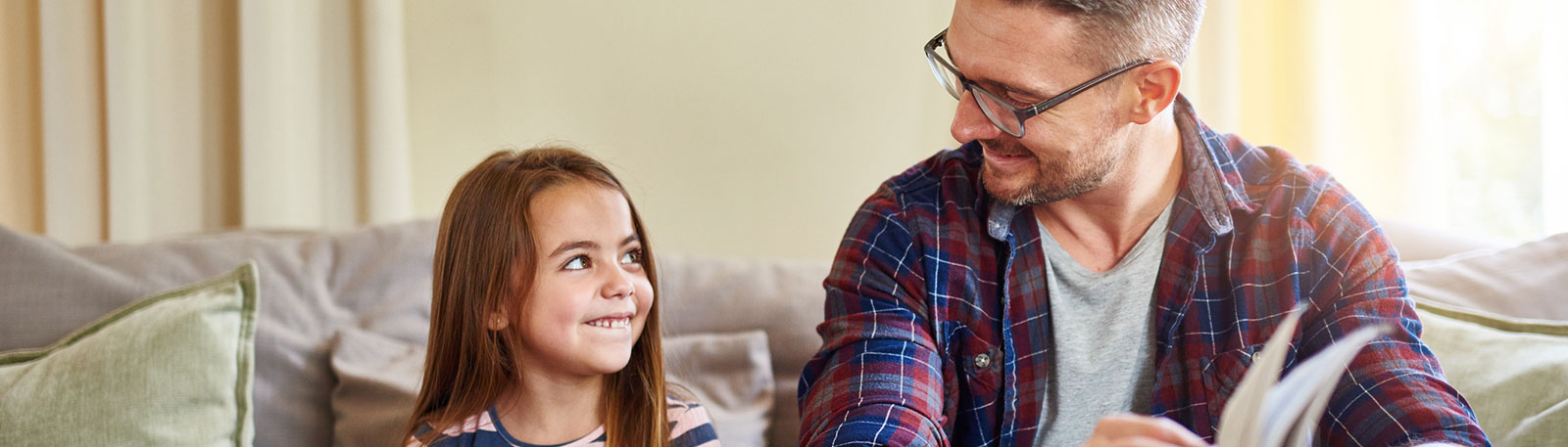 Father and daughter reading on couch