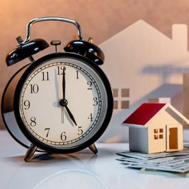 Alarm clock next to a small house